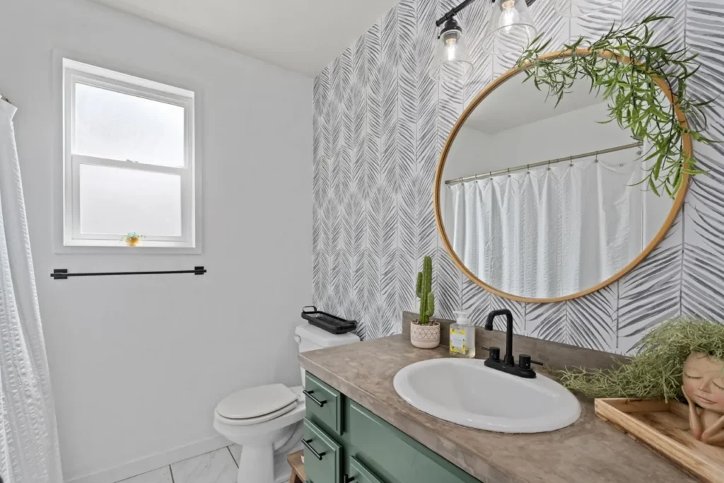 Bathroom with a round mirror, a window and green plants