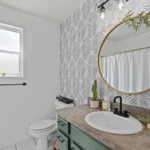 Bathroom with a round mirror, a window and green plants