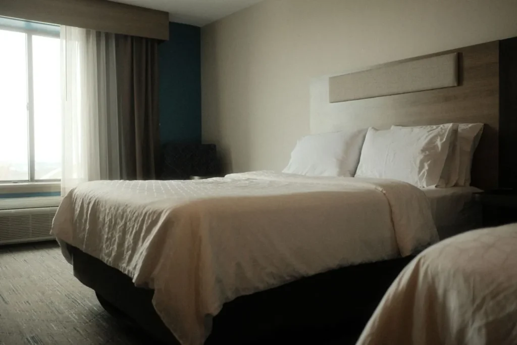Made bed in a bright bedroom with a window to one side