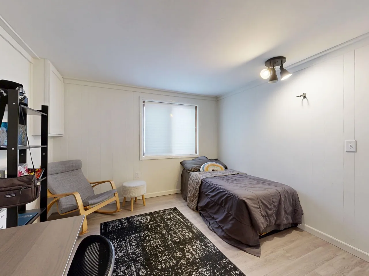 Compact bedroom with a grey bedspread, a rug and a window on the side wall