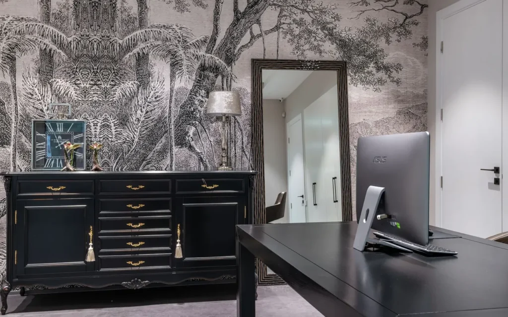Desk set against a wall below a mirror, with its back to the room