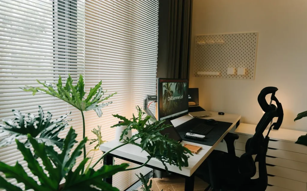 Home office desk surrounded by plants by a window