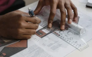 Hands drawing a floor plan with a pencil and ruler