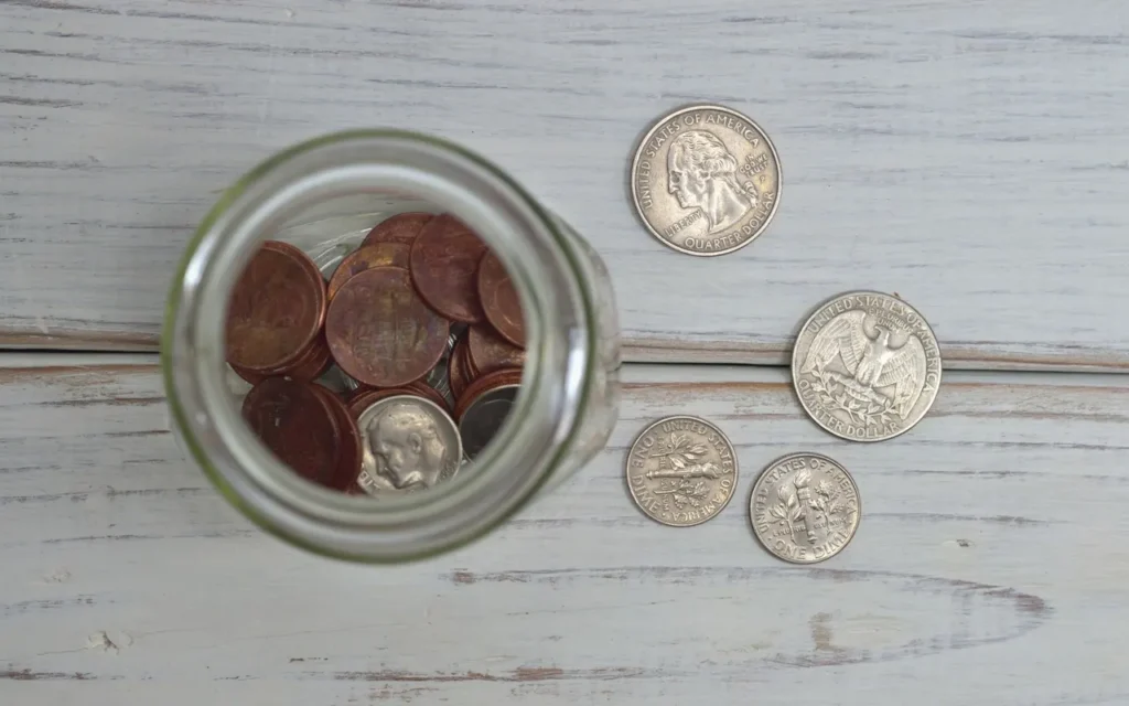 Glass jar of coins on a white wooden table