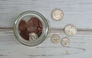 Glass jar of coins on a white wooden table