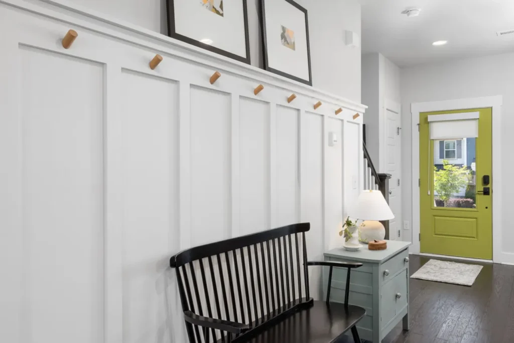 Entryway with a green front door, a black bench and white panelled walls