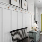 Entryway with a green front door, a black bench and white panelled walls