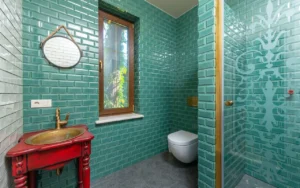Bathroom with green tiled walls and a round mirror