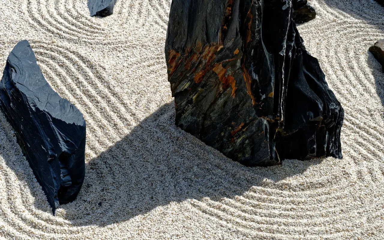 Raked sand and dark rocks in a quiet zen garden