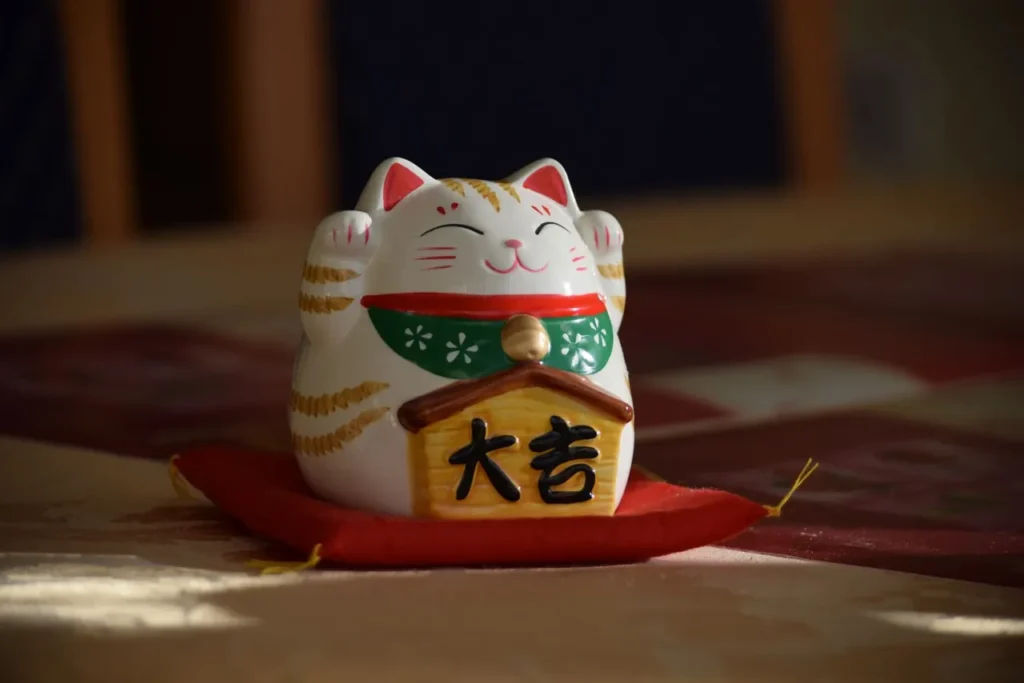 Maneki-neko lucky cat figurine on a red cushion