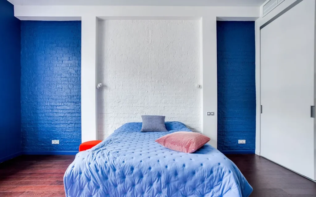 Bed with its headboard against a solid navy wall