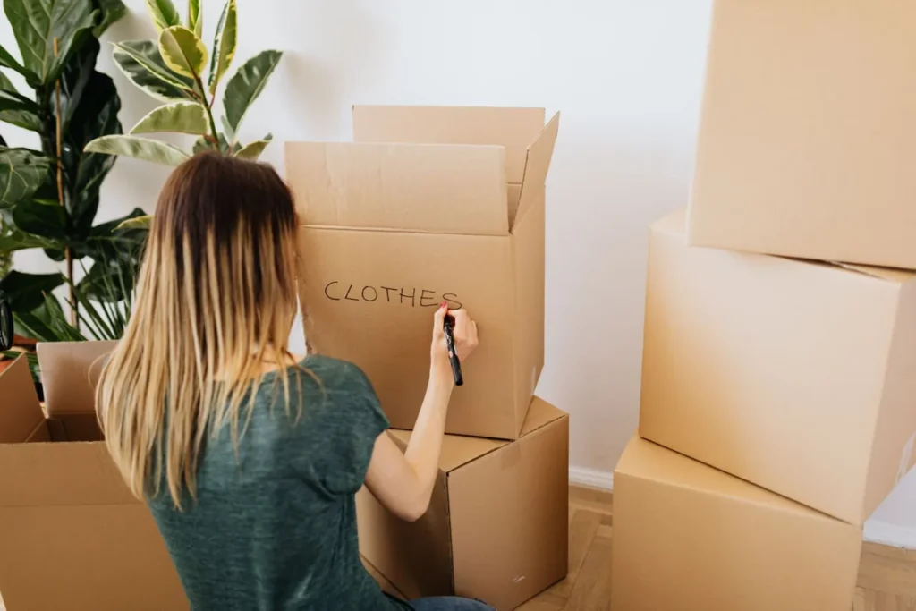 Person labelling a cardboard box while sorting belongings