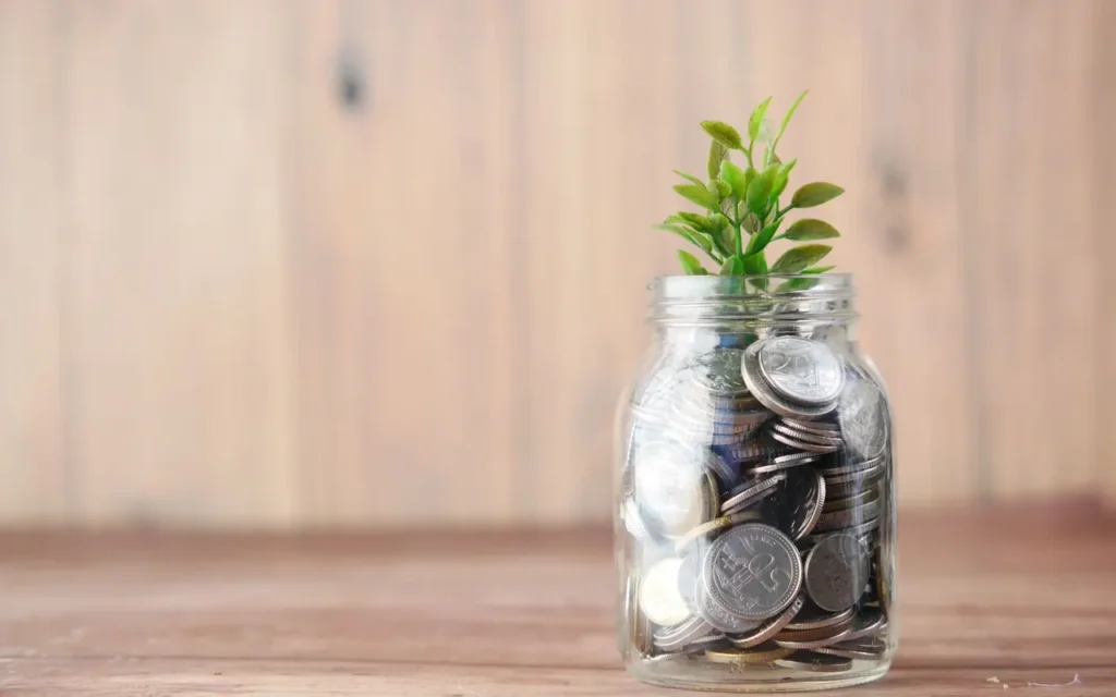 Small green seedling growing from a jar of coins