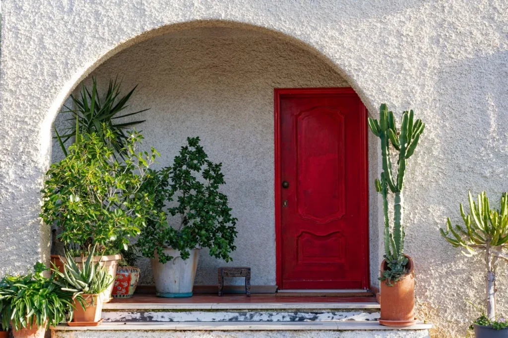 Red front door framed by potted plants