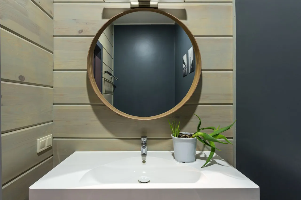 Round mirror hanging above a bathroom sink