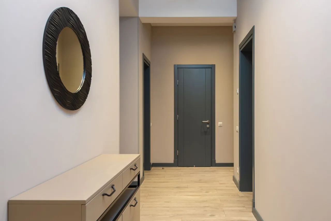 Round mirror above a cabinet on the side wall of an entrance hall