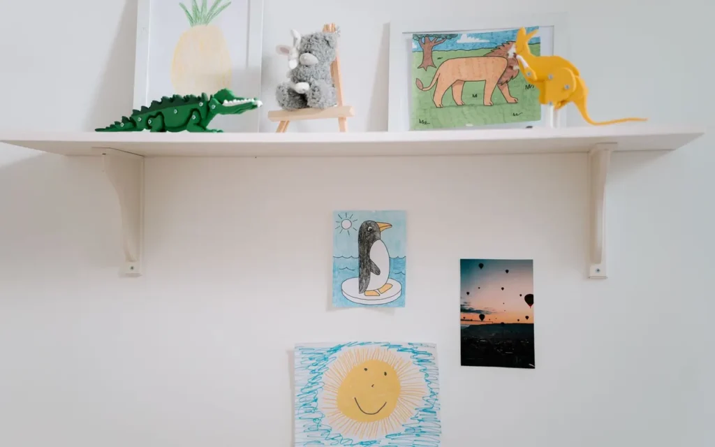 White shelf with small framed pictures and prints on a white wall
