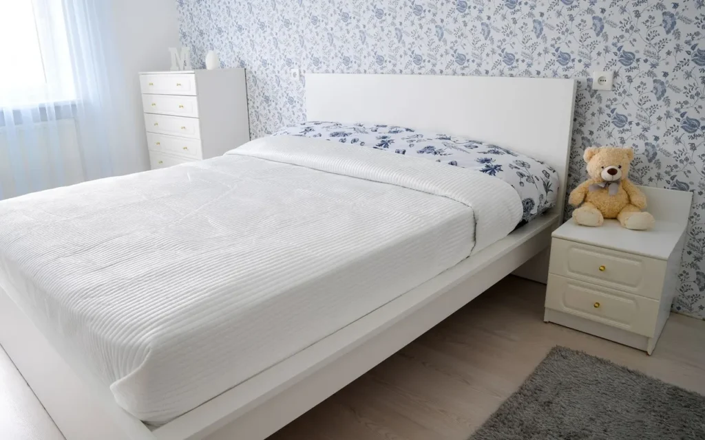 White bed against blue floral wallpaper