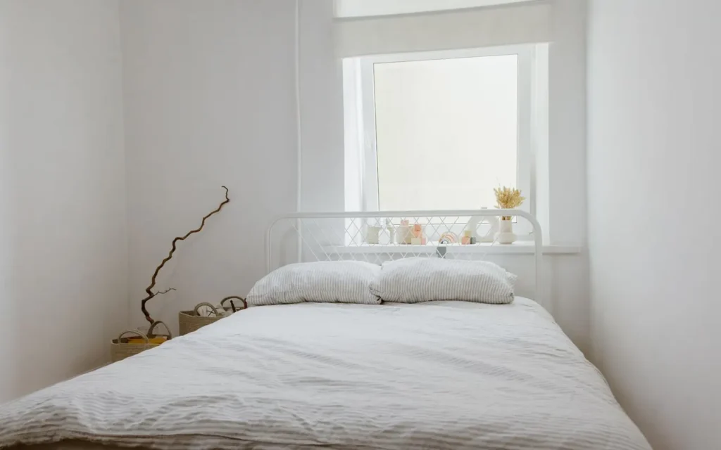 Simple white bedroom with a low bed under a window