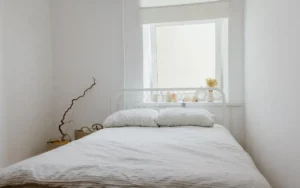 Simple white bedroom with a low bed under a window